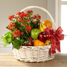 a basket filled with fruit and flowers on top of a wooden table