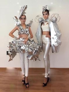 two women in silver and white outfits standing next to each other on a wooden floor