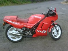 a red motorcycle parked on top of a gravel road