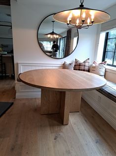 a round wooden table sitting in front of a window