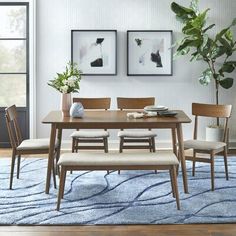 a dining table with four chairs and a bench in front of two pictures on the wall