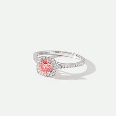 a white gold ring with an oval shaped pink diamond surrounded by small pave diamonds