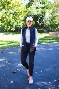 a woman standing in the middle of a park wearing black pants and a white shirt