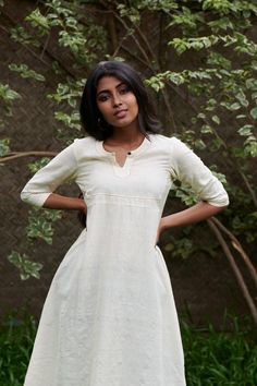 Rich buttery kora in a flared kurta with a shaped square yoke Length - 46 inchesHeight of model - 5'4" / 163cmMeasurements of model - 33.5 inch (bust) 28 inch (waist) 40 inch (hip)Model wears a size XSColour - Kora (off -white)Fabric - 100 % hand spun handwoven cottonCannot see throughCOMPOSITION100% pure cotton medium weight locally wovenTHE KAITHARI PROJECTHandspun, handwoven, designed and tailored in Kerala Fitted Beige Anarkali Kurta, Fitted Cream Dress For Transitional Season, Transitional Cream Fitted Dress, Off White Fitted Anarkali Kurta, Fitted Off White Anarkali Kurta, Fitted Off White Kurta For Transitional Season, Classic Fitted Cotton Kurta, Cream Fitted Long Sleeve Kurta, Fitted Beige Kurta For Spring