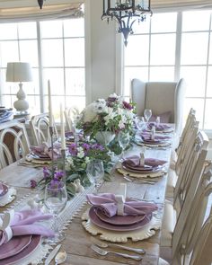 a dining room table set with purple and white place settings