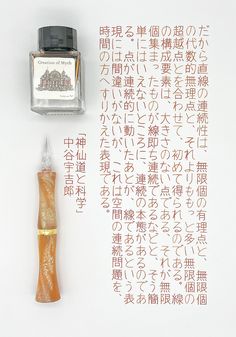 an ink pen with writing on it next to a bottle of ink and some chinese characters