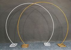 three white and yellow metal circles on wooden bases with one standing in front of the other