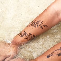 two people with tattoos on their legs are sitting in the water and one is holding her leg