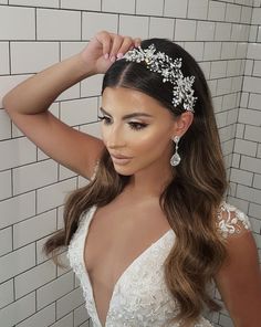 a woman in a wedding dress is posing with her hair up and wearing a tiara