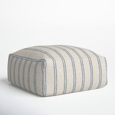 a blue and white striped poufce sitting on top of a white floor next to a wall