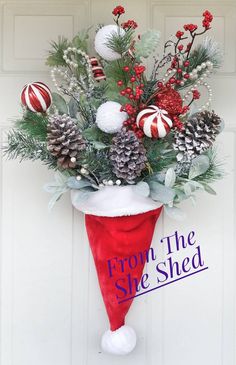 a christmas stocking hanging from the side of a door with pine cones and berries