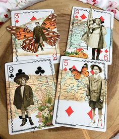 four playing cards with pictures of people and butterflies on them sitting on a wooden plate