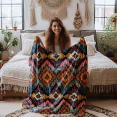 a woman sitting on the floor holding up a blanket in front of her face and smiling at the camera