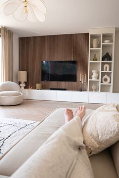 a person laying on a couch with their feet propped up in front of a television