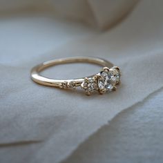 a three stone diamond ring on top of a white cloth covered bed sheet with the light shining through it