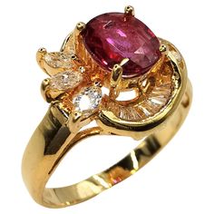 a yellow gold ring with an oval shaped red stone surrounded by small white and brown diamonds