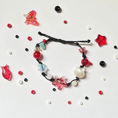 a bracelet with red beads and seashells is laying on the table next to other items