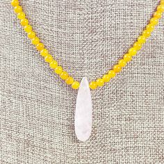 This necklace is made with yellow jade beads. The beads are 4mm round beads with a polished finish. Each bead is strung on a 100% nylon cord. A rose quartz teardrop hangs in the center of the necklace.  The necklace is finished off with a gold plated stainless steel clasp and logo charm. The necklace  is 17inches long with a 2inch extension. The necklace is also available in different gemstones. Ewelina Pas Jewelry Yellow Spiritual Beaded Necklace With Gemstone Beads, Spiritual Yellow Hand-strung Necklaces, Spiritual Yellow Hand-strung Necklace, Yellow Round Beaded Spiritual Necklace, Yellow Beaded Necklace With 8mm Beads As Gift, Yellow Necklaces With 8mm Beads For Gifts, Yellow Gemstone Beaded Necklaces, Yellow Gemstone Beaded Necklaces For Gifts, Jade Bead Necklace