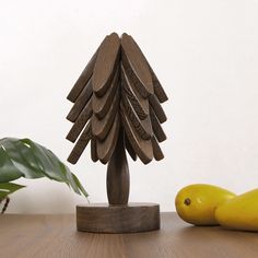 a wooden christmas tree sitting on top of a table next to two bananas and a potted plant