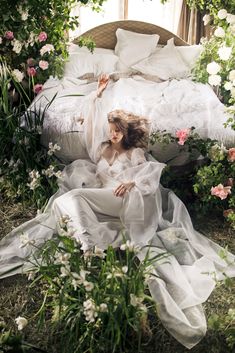 a woman laying on top of a bed surrounded by flowers