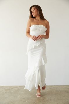 a woman in a white dress posing for the camera with her hands on her hips