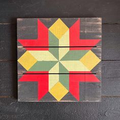 a wooden wall hanging with a colorful star design on it's side and two pieces of wood in the middle