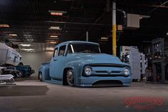 an old blue truck parked in a garage