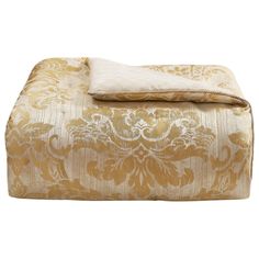 a gold and white comforter set on top of a bed next to a pillow