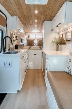 the interior of a camper with white cabinets and wood flooring is shown in this image