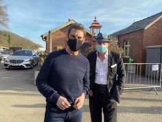 two men wearing masks standing in front of a building