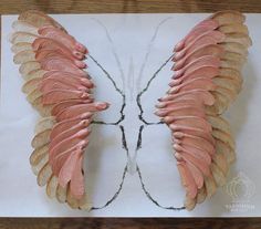 the wings of a butterfly are made out of wood and paper on top of a piece of paper