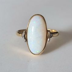 18CT Vintage opal and diamond ring  Featuring a beautiful white opal with flecks of orange, green and blue. The dainty shoulders are made up of a three leaf design, with each holding a diamond. Opal measures at height 16mm and width 7.5 Ring size UK- O US- 7 Hallmark- crown 750, (English 18CT hallmark) anchor (Birmingham assay) 'J' (year 1983) All of my pieces are offsite in secure storage and will be dispatched within one working day of purchase. Item will be presented in a leatherette ring box Opal And Diamond Ring, Unique Opal, Green Tourmaline Ring, Gift Inspiration, Tourmaline Ring, Fantasy Jewelry, Green Tourmaline, White Opal, Green And Blue