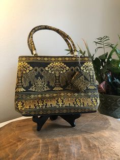 "This bag looks like it is from India but it could be from Singapore as well. It looks well made and has embroidered, ornate elephants and other designs. The tiny coin purse is also attached. It looks like it was never used. No damage or marks on it. We disclose as much as we know about an item. Our items are vintage, gently used pieces, (with the exception of a few handmade products.) They may have flaws or wear. Check out the pictures to ensure you know what you are buying. All products are \" Traditional Gold Shoulder Bag For Travel, Traditional Gold Shoulder Bag For Daily Use, Gold Embroidered Tote Bag, Gold Rectangular Shoulder Bag For Festivals, Gold Handheld Shoulder Bag Gift, Black Rectangular Shoulder Bag For Festivals, Gold Rectangular Coin Purse For Daily Use, Rectangular Gold Coin Purse For Daily Use, Gold Rectangular Coin Purse With Removable Pouch