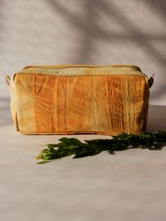 a small yellow bag sitting on top of a table next to a leafy plant