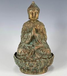 a bronze buddha statue sitting on top of a white surface