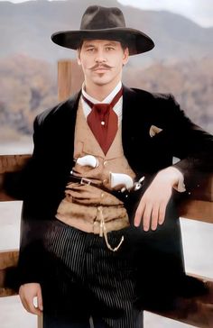 a man in a suit and hat is sitting on a bench with his hand on his hip