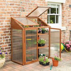 a small wooden greenhouse with plants growing inside