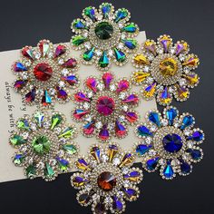 an assortment of colorful jeweled brooches on a white card with a black background