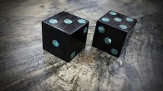 two black dices sitting on top of a wooden table