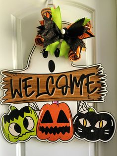 a welcome sign hanging from the front door with halloween decorations on it's side