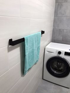 a white washer sitting next to a dryer in a bathroom under a towel