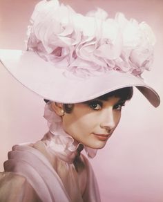 a woman wearing a pink hat with flowers on it's brimmed top