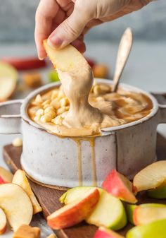 a person dipping an apple into a pot of oatmeal