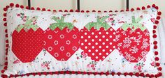 a pillow with three strawberrys on it sitting on top of a white headboard