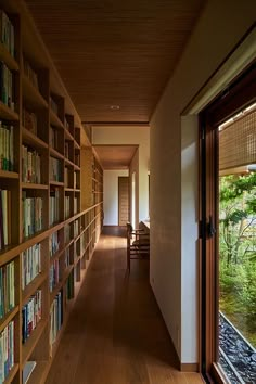 a long hallway with bookshelves full of books on the walls and wooden floors