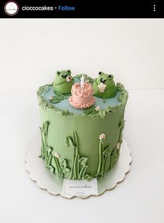 there is a green cake with frog decorations on it and the name instagramn