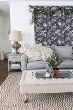 a living room with a couch, coffee table and christmas decorations on the wall behind it