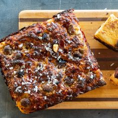 two slices of pizza sitting on top of a cutting board next to other food items