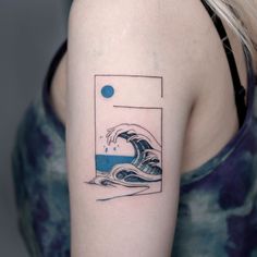 a woman's arm with a blue and white wave tattoo on her left shoulder