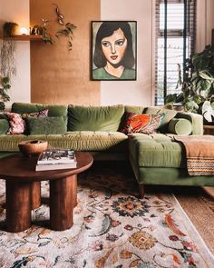 a living room with green couches and paintings on the wall above them, along with wicker chairs